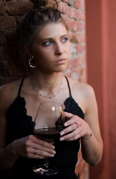 Photo beautiful woman holding wineglass while looking away