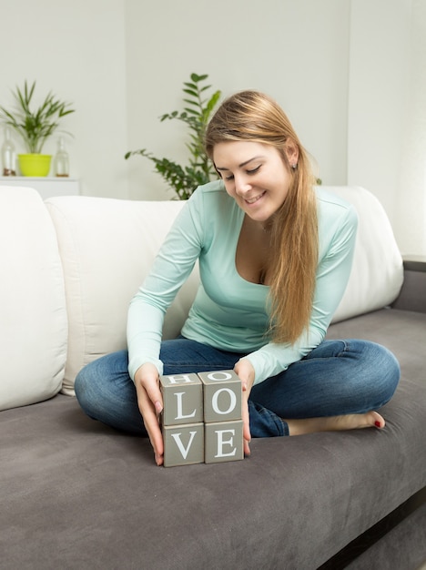 Beautiful woman holding wooden bricks with letters making word Love