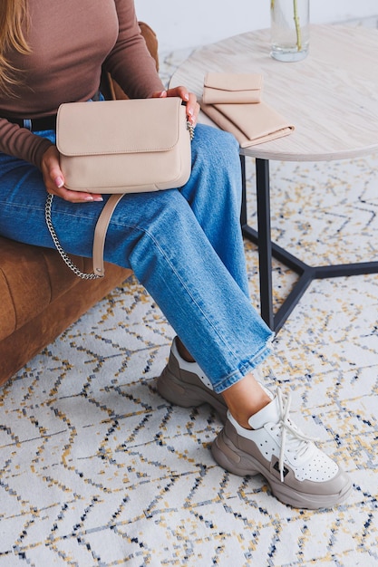 A beautiful woman holds a beige leather bag in her hands A small women's cocktail bag