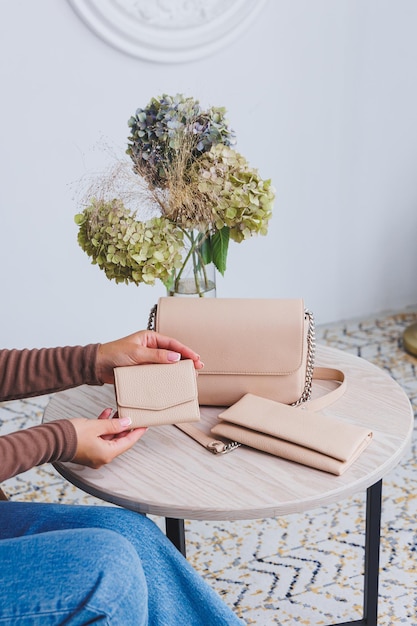 A beautiful woman holds a beige leather purse in her hands Small women's handbag