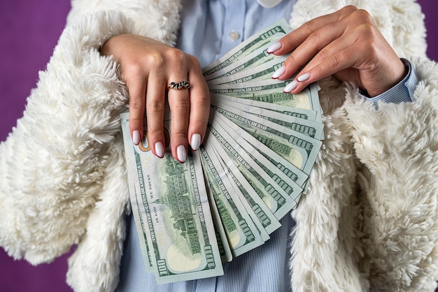 Beautiful woman holds dollars with beautiful hands a large amount