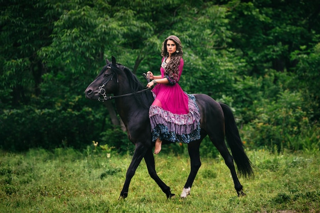 Beautiful woman on a horse dressed in long violet dress