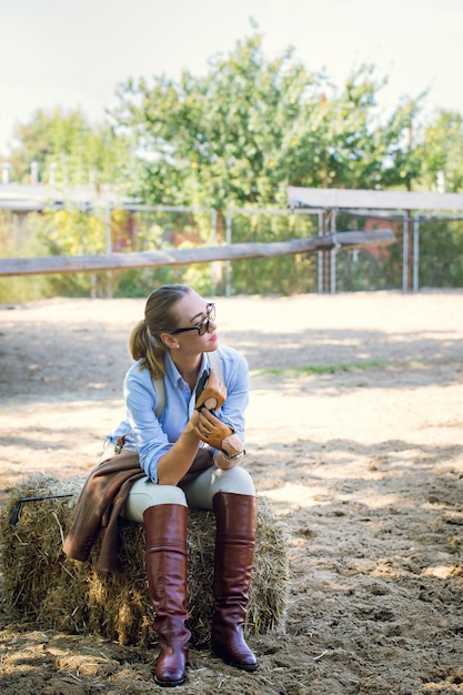 A beautiful woman in a horse riding costume resting in the hayloft