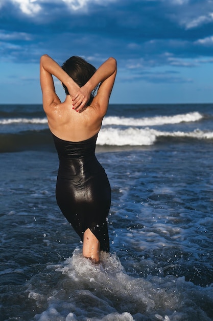 Фото Красивая женщина в черном платье наслаждается морем.