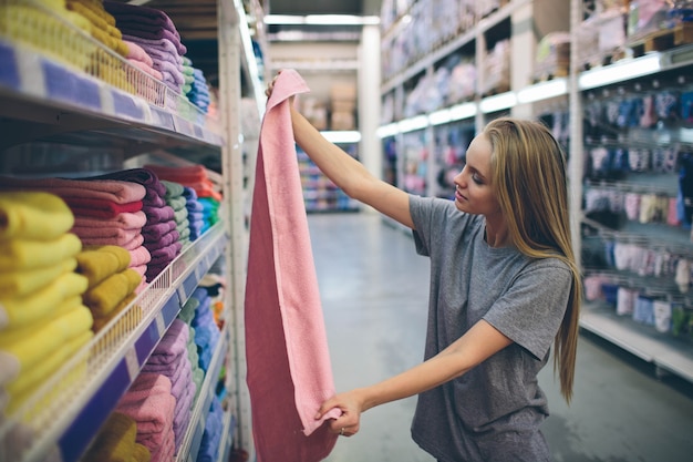 Beautiful woman inspecting and buying towels in supermarket.