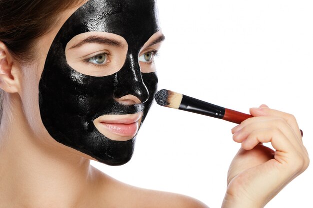 La bella donna sta applicando la maschera nera purificante sul suo fronte