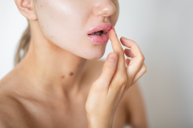 Foto la bella donna sta applicando la macchia sulle sue labbra