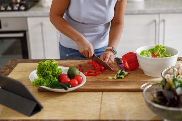 La bella donna sta cucinando piatti deliziosi nella sua cucina di casa