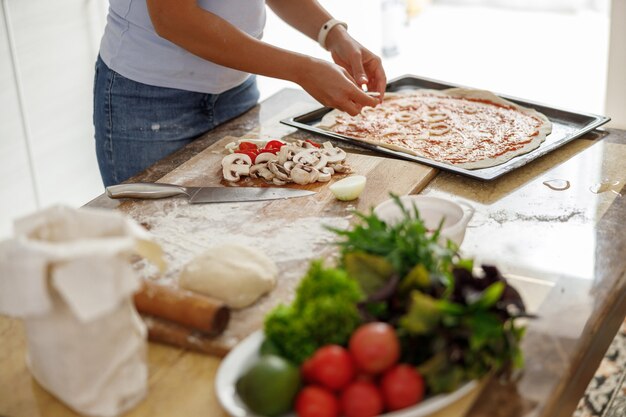 Foto la bella donna sta cucinando piatti deliziosi nella sua cucina di casa