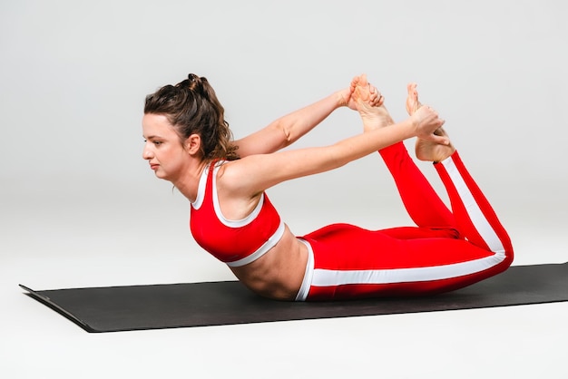 A beautiful woman is exercising in a yoga class for weight loss in the red sportwear