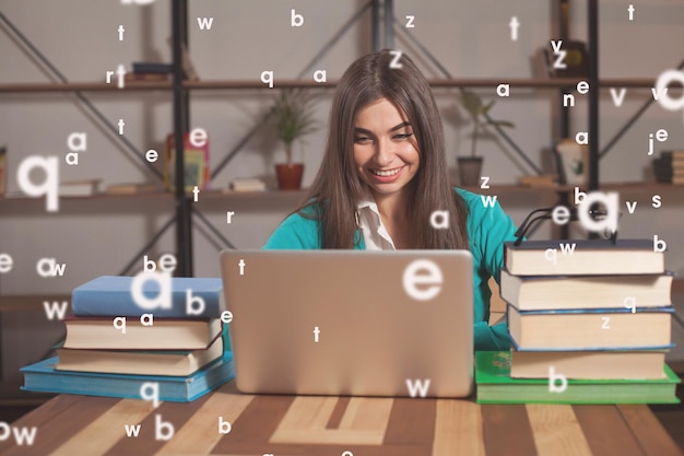 Foto la bella donna è felice del suo lavoro di successo con laptop grigio e libri al tavolo