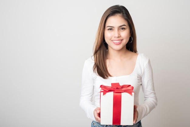 Beautiful woman is holding gift box on white wall