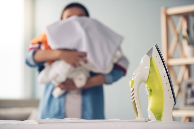 Beautiful woman is holding laundry for ironing at home