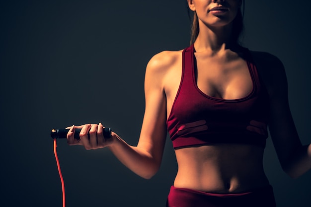 The beautiful woman is jumping with a skipping rope in the gym