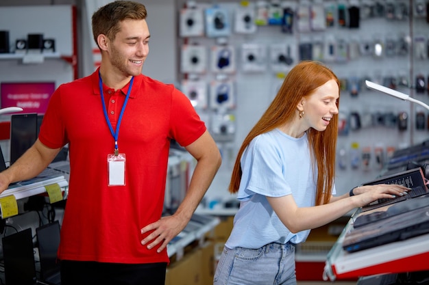 Photo beautiful woman is looking for the best laptop in computer department