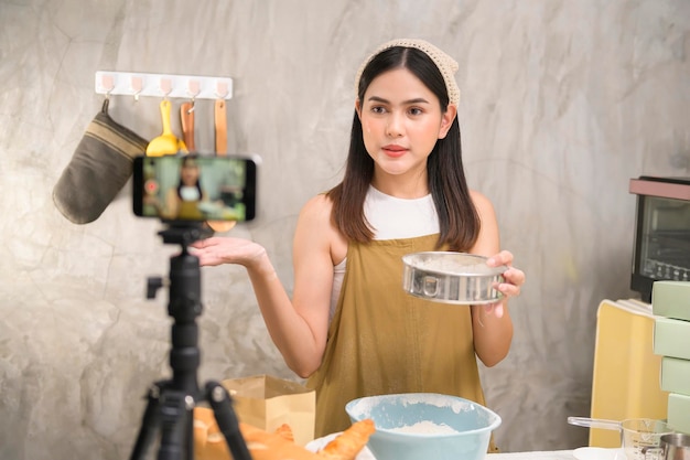 Beautiful woman is making bakery while live streaming or recording video on social media in her house coffee shop business concept