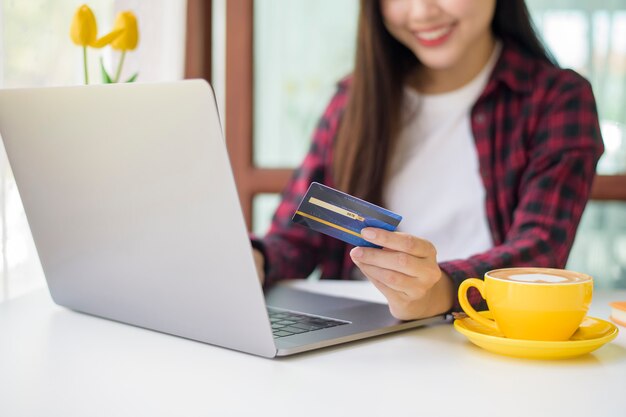 Beautiful woman is online shopping with credit card in coffee shop