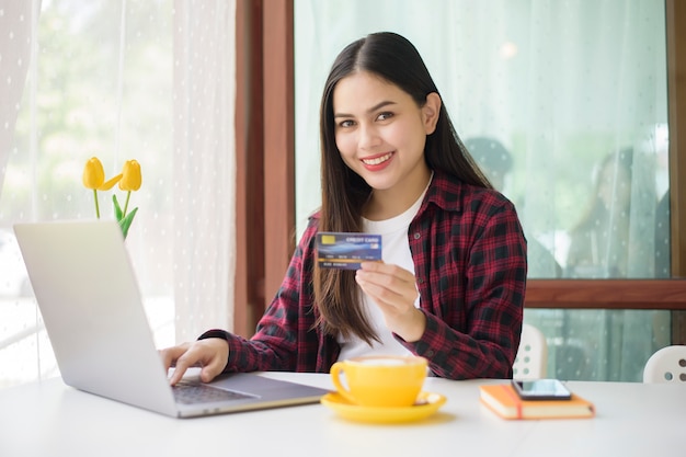 美しい女性はコーヒーショップでクレジットカードでのオンラインショッピング