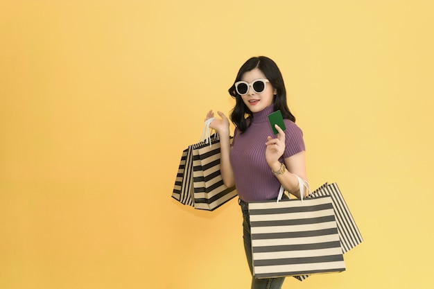 Beautiful woman is shopping in the mall.Woman wearing glasses and hat holding shopping bag fashion in department store.