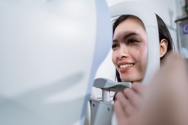 A beautiful woman is undergoing an examination using an eye examiner in the eye clinic room