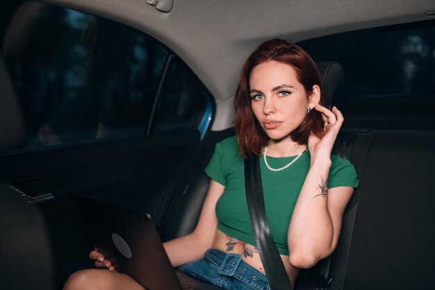 Beautiful woman is using laptop while sitting on back seat