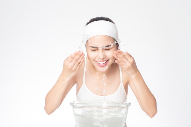 Beautiful woman is washing her face on white background