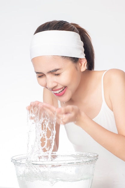 Beautiful woman is washing her face on white background 