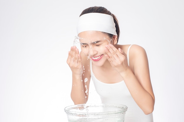 Beautiful woman is washing her face on white background 