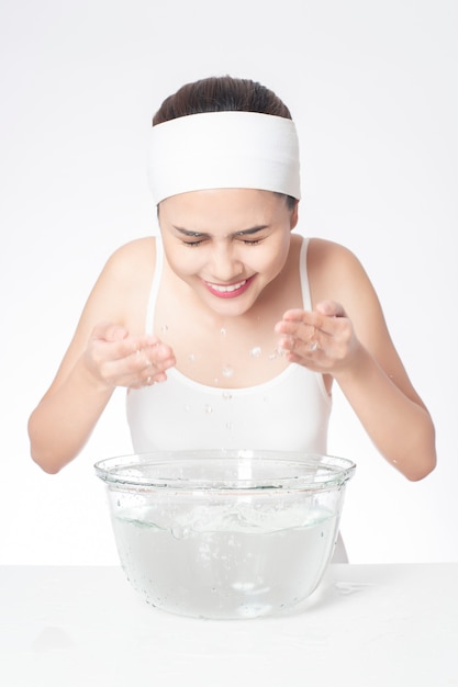 Beautiful woman is washing her face on white background 