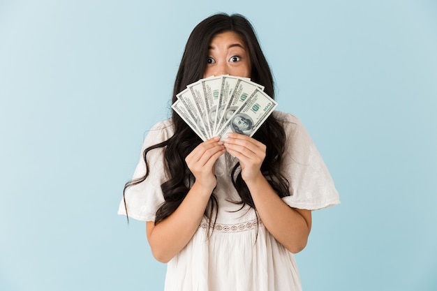 Beautiful woman isolated over blue wall holding money