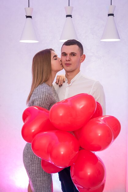 Красивая женщина, целуя своего мужчину. Празднование Дня святого Валентина с воздушными шарами
