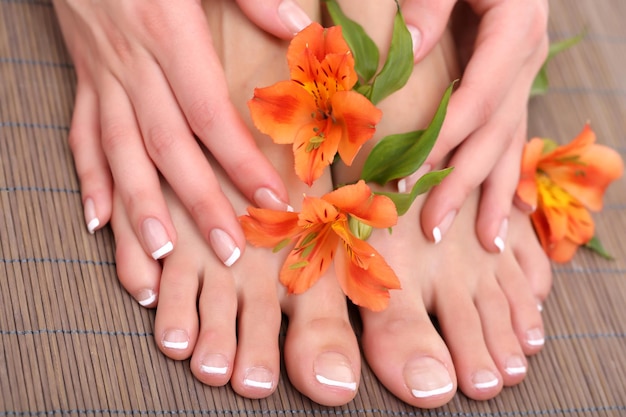 Beautiful woman legs hands on bamboo mat