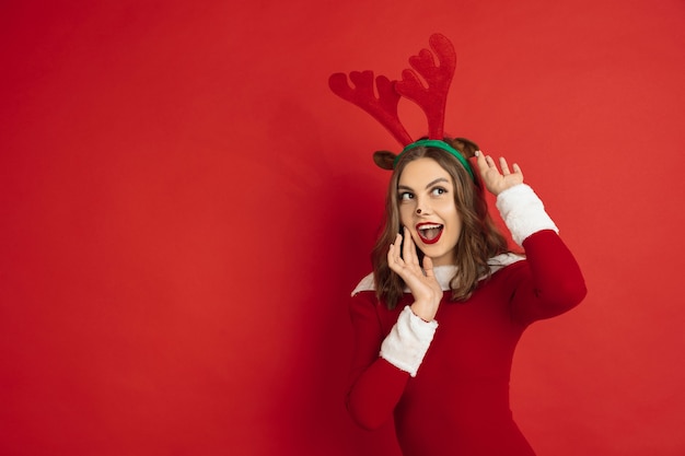 Beautiful woman like christmas deer isolated on red surface concept of  new years winter mood holidays