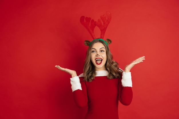 Beautiful woman like christmas deer isolated on red wall