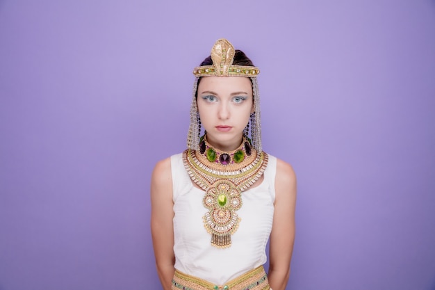 Beautiful woman like cleopatra in ancient egyptian costume with serious confident expression on purple