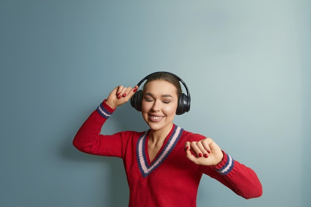 Beautiful woman listening music with wireless headphones Girl uses wireless earphones and dancing