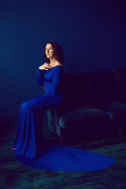 Beautiful woman in long blue dress in studio