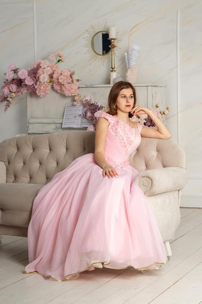 A beautiful woman in a long pink dress in a hall with flowers The girl is pretty Spring PHOTOSESSION