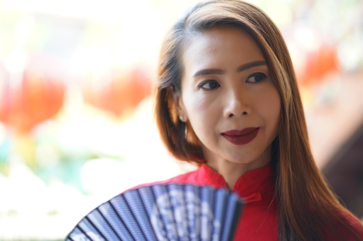 Photo beautiful woman looking away holding hand fan against defocused background