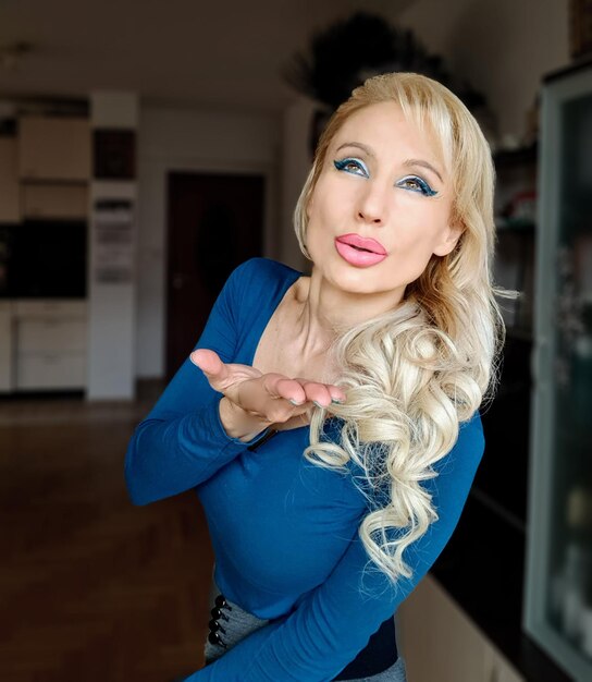 Photo beautiful woman looking away while blowing a kiss at home