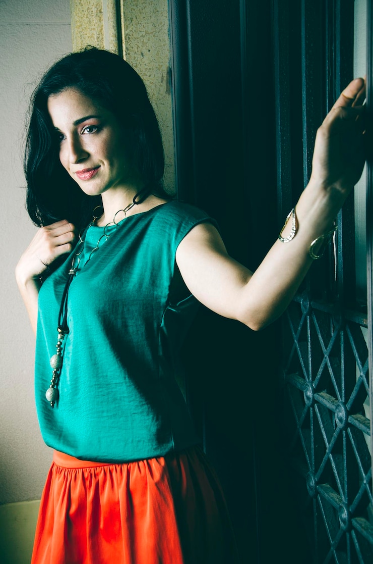 फोटो beautiful woman looking away while standing by metal gate