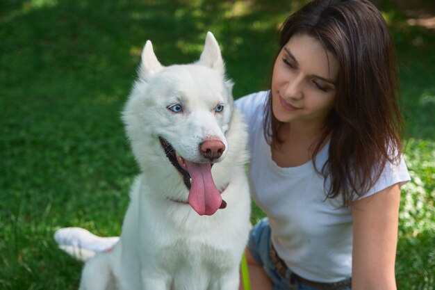 Beautiful woman looking to her adorable white dog with blue eyes