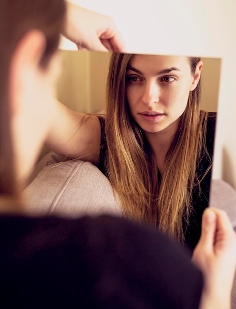 Photo beautiful woman looking in mirror at home