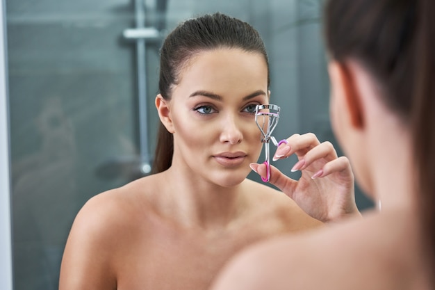 Photo beautiful woman looking on reflection in the mirror after shower