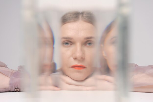 Beautiful woman looking through glass water looks into camera
bright orange