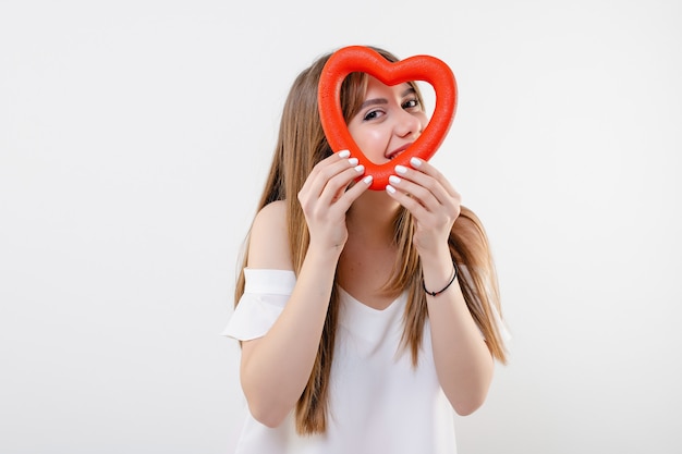 Beautiful woman looking through red heart shape isolated