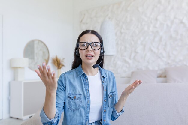 Beautiful woman looking at web camera nervous and arguing with interlocutor using headset for video