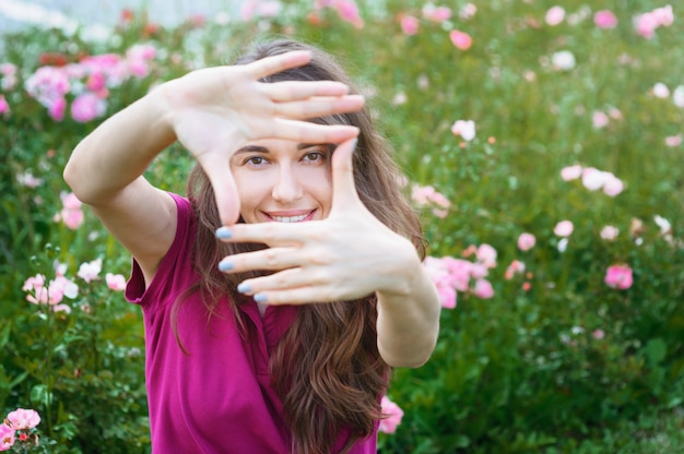 Beautiful woman looks through fingers frame