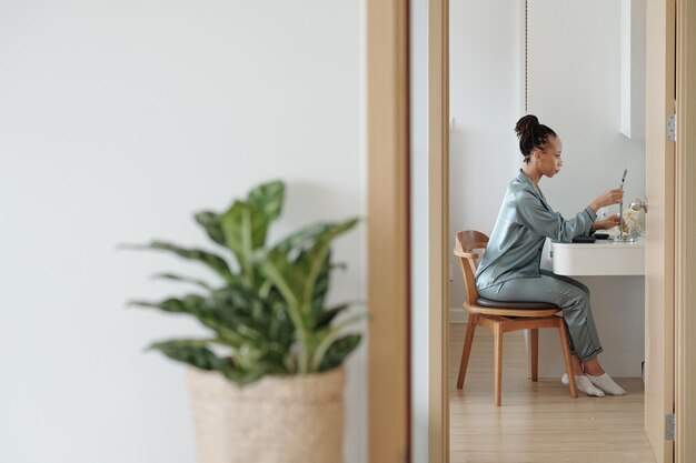 Beautiful woman in loungewear setting magnifying mirror at vanity in her bedroom