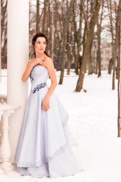 Beautiful woman in a luxurious blue fairytale dress in a snowy forest